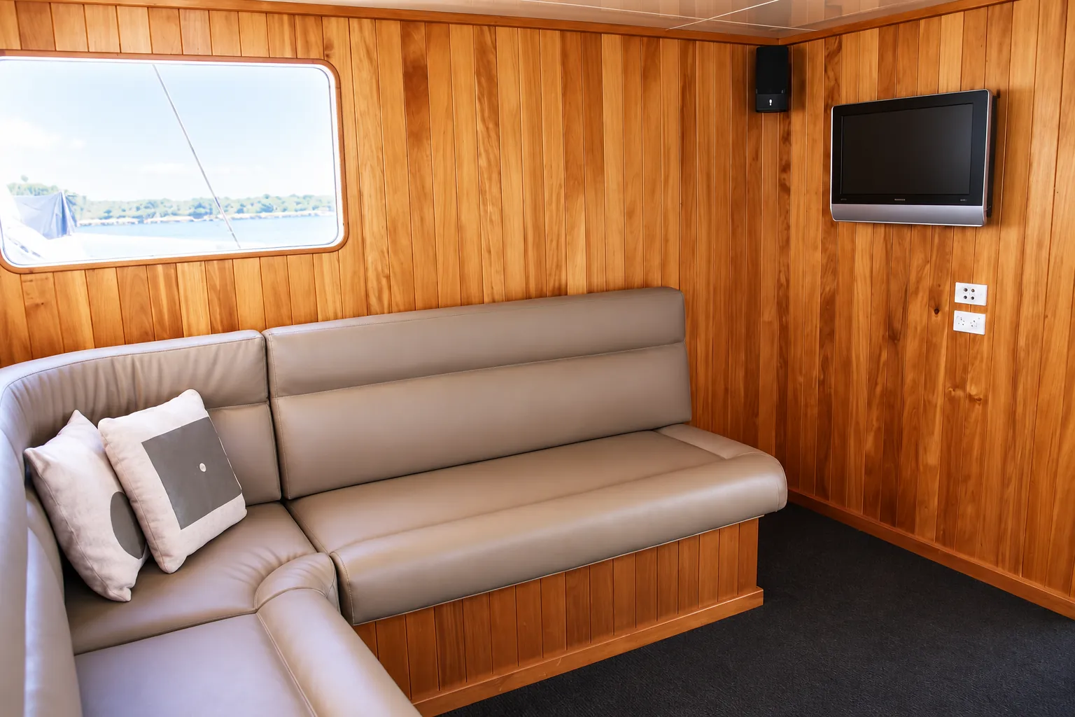 Lounge corner on Kiwa II with leather seating, timber panelling and a wall-mounted TV