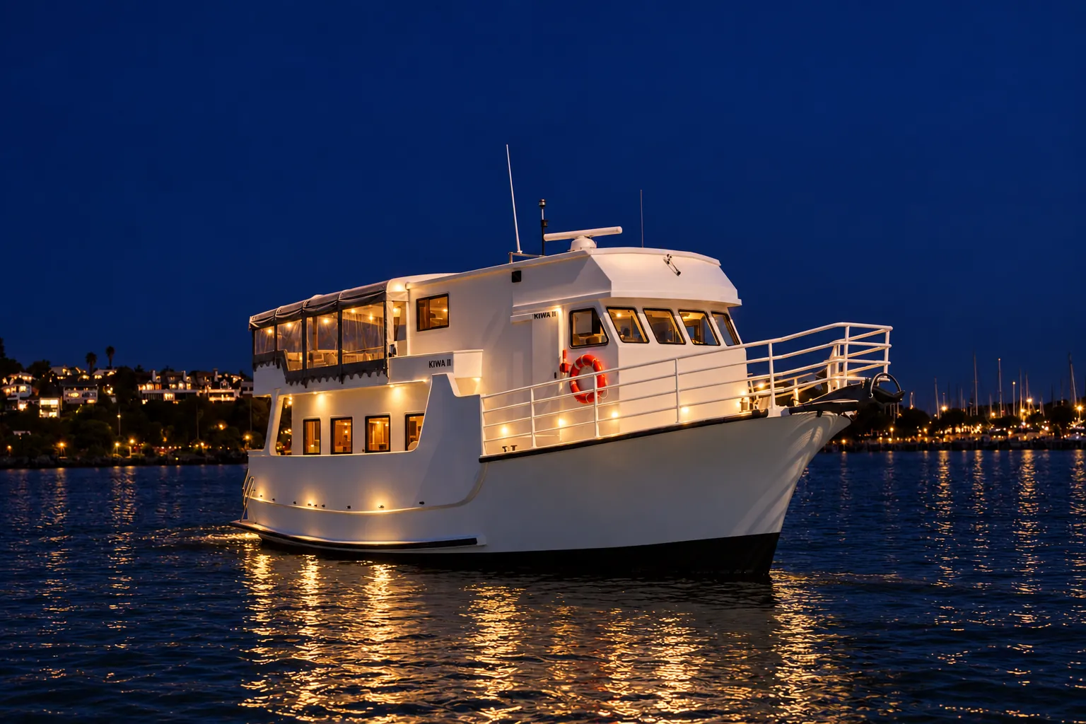 kiwa-ii-night-cruise Kiwa II lit up at night on Auckland Harbour, with marina and hillside lights behind