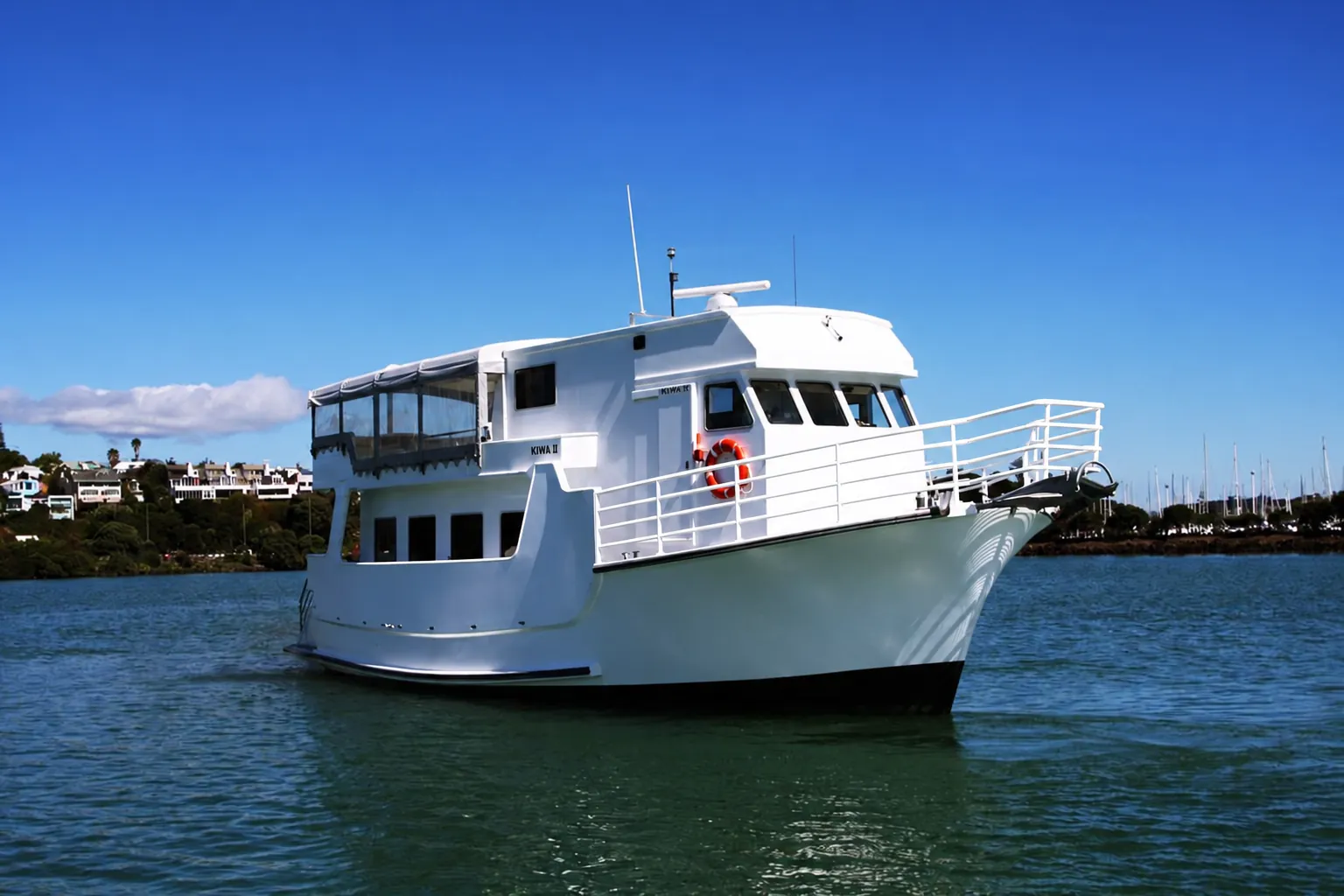 Kiwa II cruising on Auckland Harbour on a sunny day, showing its upper and lower decks