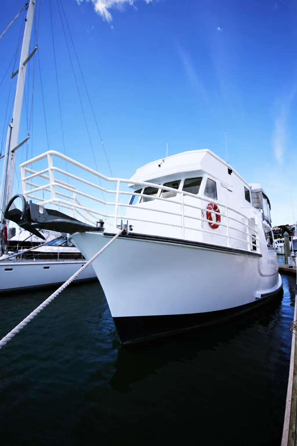 Bow of Kiwa II moored at the marina, showing the white bow rail and wheelhouse